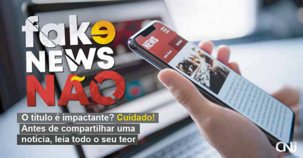 O anúncio, do Conselho Nacional de Justiça, apresenta a foto de uma mão que segura um celular que está com a tela aberta em uma página de notícias. Ao fundo, há a imagem de um notebook aberto. Ao lado das imagens, há o título “Fake News Não”, seguido do texto: “O título é impactante? Cuidado! Antes de compartilhar uma notícia, leia todo o seu teor”.