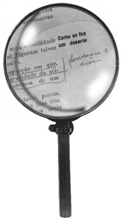 detalhe da instalação: uma lupa de cabo escuro apoiada sobre uma página impressa amarelada de um livro antigo, ampliando trechos de texto e anotações manuscritas a lápis feitas nas margens