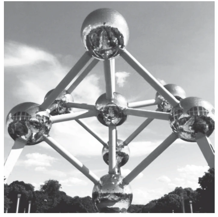 fotografia do Atomium, estrutura metálica em forma de cubo apoiado sobre um vértice, com nove esferas reflexivas ligadas por tubos cilíndricos, vista de baixo contra o céu