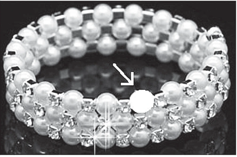 fotografia de uma pulseira de pérolas brancas, com uma seta apontando para o espaço vazio onde falta uma das pérolas